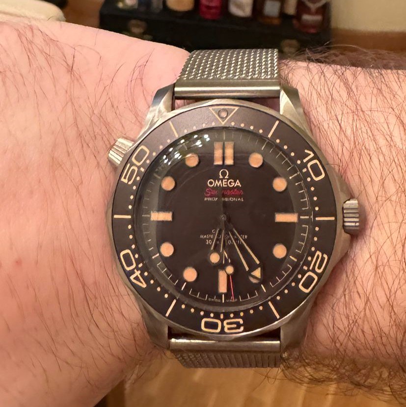 Omega Seamaster Diver 300M 007 Edition on the wrist, with a titanium case, brown dial and mesh bracelet
