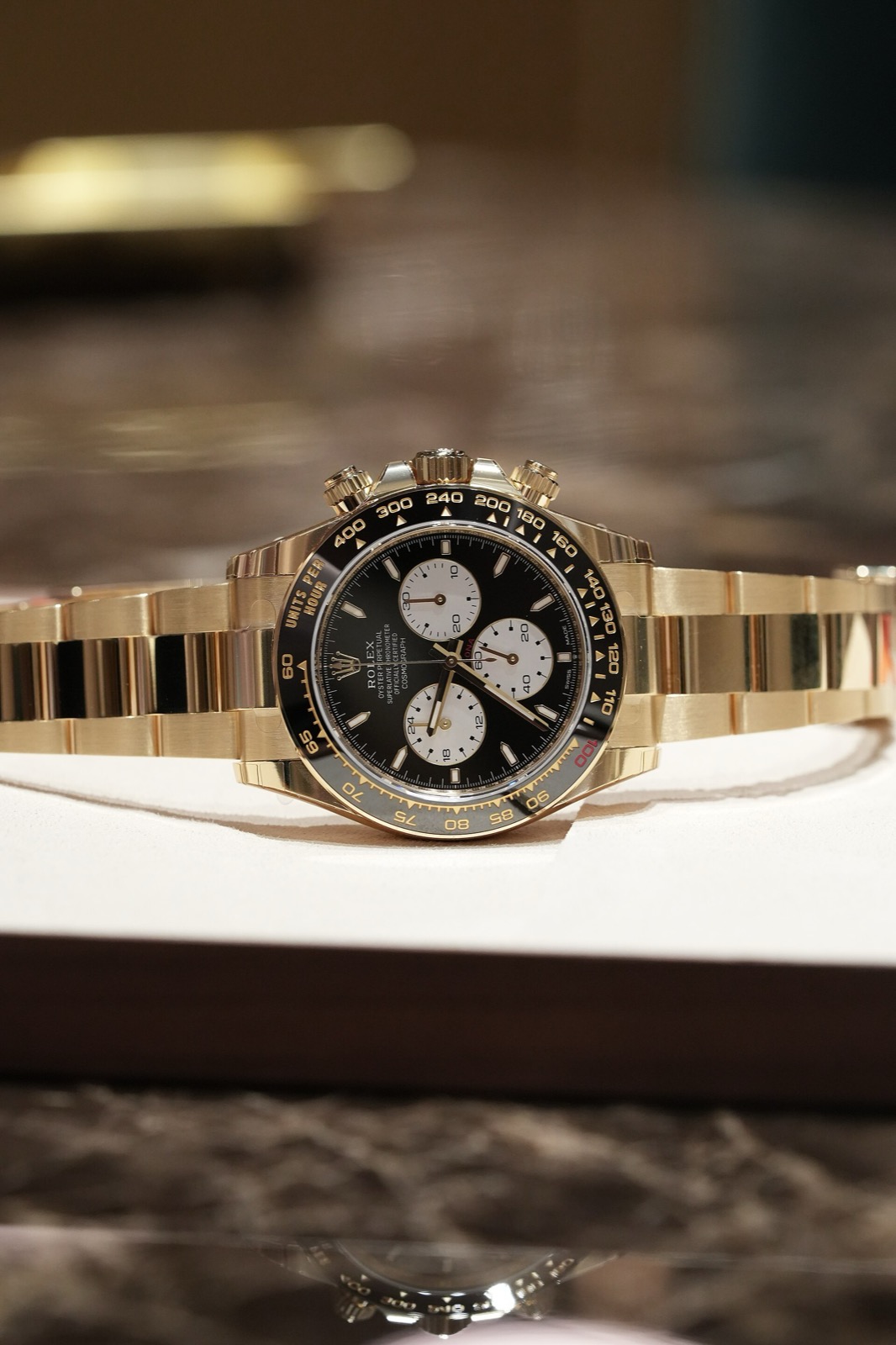 Vitrinde siyah kadranlı, beyaz sayaçlı ve siyah seramik bezelli sarı altın Rolex Le Mans Daytona ref. 126528LN