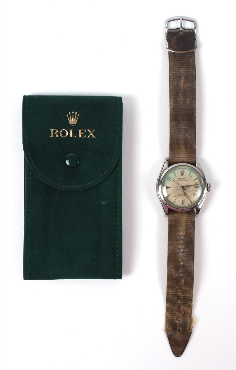 A 1953 Rolex Oyster Perpetual presented to Edmund Hillary, on a fabric strap next to a green Rolex pouch